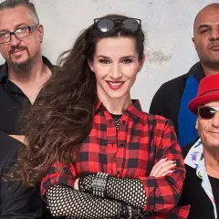 Zespół Maanam w nowym składzie: wokalistka w kratę, gitarzysta w czerwonym kapeluszu i reszta ekipy gotowa na scenę.