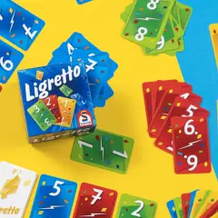 Kolorowe karty do gry Ligretto, z numerami i błyskawicami, leżą na żółtym i niebieskim tle. Poznaj ligretto zasady i zacznij grę!