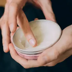 Palec zanurza się w paście do włosów, pokazując, jak używać tego produktu do stylizacji.