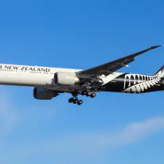 Boeing 777 Air New Zealand z charakterystycznym czarnym malowaniem na ogonie, w locie na tle błękitnego nieba.