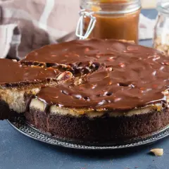 Gâteau façon Snickers, avec une base chocolatée, une couche crémeuse, du caramel coulant et une ganache au chocolat parsemée de cacahuètes. Un délice !
