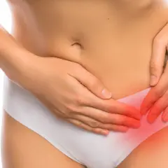 Kobieta odczuwa ból jajnika po okresie, trzymając się za podbrzusze.