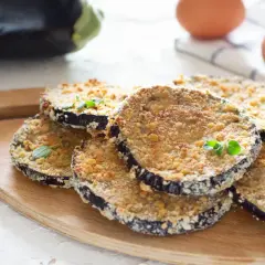 Cotolette di melanzane dorate e croccanti, guarnite con erbe aromatiche fresche, pronte per essere gustate.