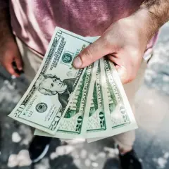 Dłoń trzyma kilka banknotów po 20 dolarów. Zastanawiasz się, skąd wziąć kasę na spełnienie marzeń?