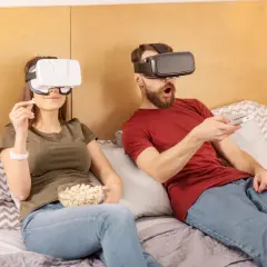 Para ogląda filmy VR na kanapie, trzymając popcorn i pilota.