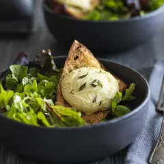Salade fraîche avec une tranche de pain grillé et une quenelle de **chèvre chaud** garnie d'herbes.