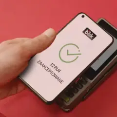 Zbliżeniowa płatność telefonem przez blik. Na ekranie telefonu widnieje potwierdzenie transakcji 12 PLN.