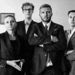 Cztery osoby w garniturach, w tym dwie kobiety i dwóch mężczyzn, stoją w rzędzie.