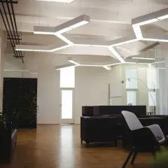 Nowoczesne biuro z designerskim oświetleniem. **LED zintegrowany co to znaczy?** To światło wbudowane w sufit, tworzące geometryczne wzory.