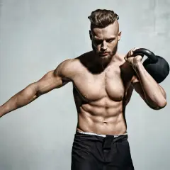 Mężczyzna z wyrzeźbionym ciałem trzyma kettlebell, gotowy do treningu. Czy to sekret, jak nabrać masy mięśniowej w 2 tygodnie?