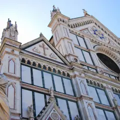 Statua di un poeta toscano davanti alla facciata in marmo di una chiesa fiorentina.