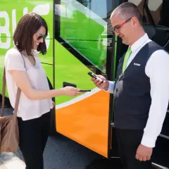 Kobieta pokazuje bilet na telefonie kierowcy Flixbus. Warto szukać flixbus promocje na podróże!