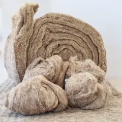 Rolka i kłęby naturalnej wełny, idealne do ekologicznego ocieplenia domu.
