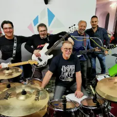 Cinque musicisti sorridenti con chitarre e batteria, pronti a suonare. Potrebbero essere tra i prossimi gruppi musicali veneti famosi.
