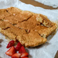 Sega havrerutor på bakplåtspapper, med färska jordgubbar vid sidan om. Perfekt fika!