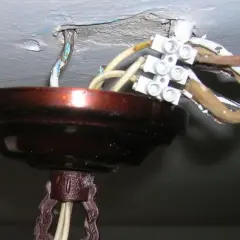 Podłączanie nowego żyrandola do starej instalacji: widoczne przewody i kostka elektryczna przy suficie.