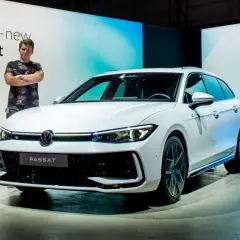 Mężczyzna stoi obok białego kombi, prezentując nowy model Passat B9.
