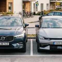 Två elbilar, en Volvo och en Kia, parkerade framför ett modernt hus. Kanske redo för en resa med klimatbonus elbil.