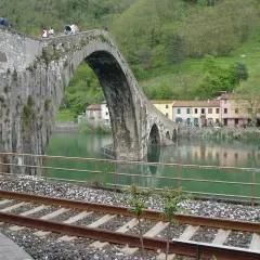 Ponte del Diavolo a Borgo a Mozzano, con case colorate e un fiume verde.