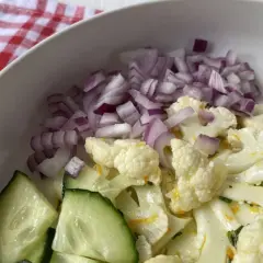 Ensalada de coliflor fresca con pepino y cebolla morada picada.
