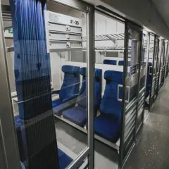Wnętrze wagonu z przedziałami intercity 2 klasa. Puste, niebieskie siedzenia czekają na pasażerów.