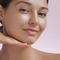 Strahlendes Gesicht einer Frau, die ihr Kinn berührt. Die Haut wirkt glatt und jugendlich, ein Zeichen für die positive retinol wirkung.
