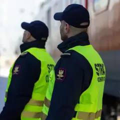 Strażnicy kolejowi w kamizelkach odblaskowych, czuwający nad bezpieczeństwem zgodnie z ustawą o straży ochrony kolei.
