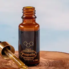 Kropla propolisu na pipetce obok buteleczki. Naturalne wsparcie dla zdrowia, odkryj jego wszechstronne zastosowanie.