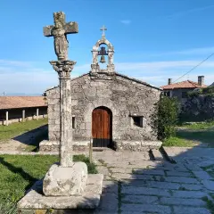 Crucero y ermita de piedra en el Castro de Santa Trega, bajo un cielo azul.