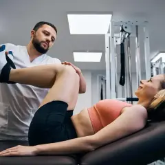 Fizjoterapeuta pomaga pacjentce w ćwiczeniach rehabilitacyjnych. Osteopata wspiera powrót do zdrowia.