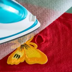 Napraw dziurę w kurtce puchowej jak naprawić, używając naszywki z motylem i żelazka.
