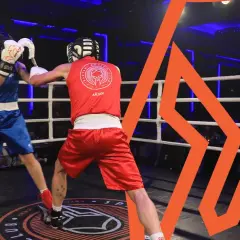 Two boxers in the lightest boxing weight class spar in a ring, one in blue, the other in red.