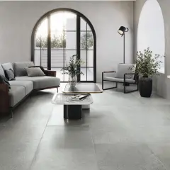 Nowoczesny salon z szarymi płytkami pod ogrzewanie podłogowe, wygodną sofą i designerskimi meblami.
