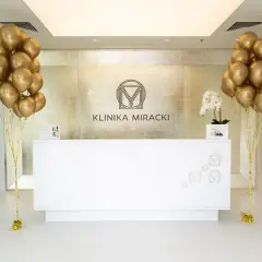 Recepcja kliniki estetycznej z bukietami złotych balonów i rzeźbą.