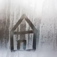 Casa dibujada en ventana empañada. El vapor de agua en el cristal muestra que es la humedad relativa.