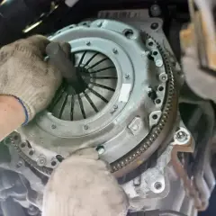 Mécanicien travaillant sur un embrayage. La question "combien de temps pour changer un embrayage" est souvent posée par les automobilistes.