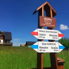 Rozdroże szlaków GSB i Karpackiego w Ropkach. Wskazówki pokazują kierunki do Ustronia, Wołosatego, Rzeszowa i Grybowa.