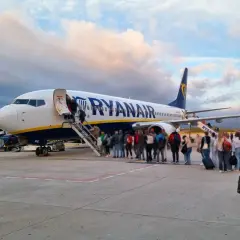 Pasażerowie wsiadają do samolotu Ryanair. W tle chmury i góry. To jak faktura za podróż, która właśnie się zaczyna.
