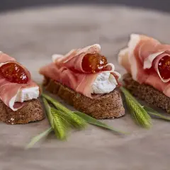 Drei kleine Brote mit Frischkäse, Feigenmarmelade und zartem **prosciutto schinken**.
