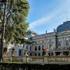 Majestatyczny pałac poznański z ozdobną balustradą i kwitnącymi kwiatami, otoczony zielenią.