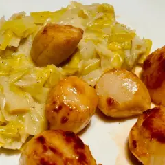Saint-Jacques poêlées sur un lit de fondue de poireaux crémeuse, un plat savoureux et réconfortant.