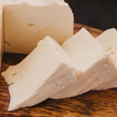 Queso de cabra fresco y cortado en cuñas sobre tabla de madera. Ideal para ensaladas, con pocas calorias.