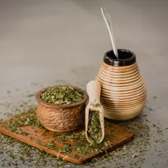 Naczynie z yerba mate i bombilla. Susz rozsypany na desce. Czy yerba mate ma właściwości negatywne?