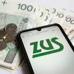 Złotówki i monety na tle ekranu telefonu z logo ZUS. Sprawdź, ile jest zasiłku pogrzebowego.