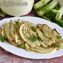 Finocchi in friggitrice ad aria, dorati e profumati, serviti su un piatto bianco con guarnizione di aneto fresco.