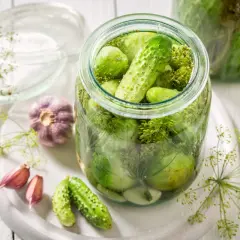 Tarro de pepinillos en vinagre, ajo y eneldo. Considera las pepinillos en vinagre contraindicaciones si tienes problemas digestivos.