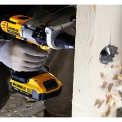 Ręka w rękawicy trzyma wiertarkę DeWalt, która wierci otwór w drewnie. Pokazano, jak włożyć wiertło do wiertarki.