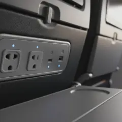 W samolotach są gniazdka! Widok na panel z gniazdkami elektrycznymi i portami USB w fotelu samolotowym, gotowy do ładowania urządzeń.