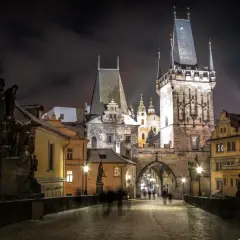 Most Karola w Pradze nocą, ośnieżony, z wieżami i rzeźbami. Idealne miejsce na wycieczki objazdowe po Europie.