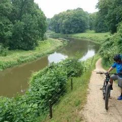 Rowerzysta na ścieżce w Parku Mużakowskim. Malownicze trasy rowerowe wzdłuż rzeki zachęcają do aktywnego wypoczynku.